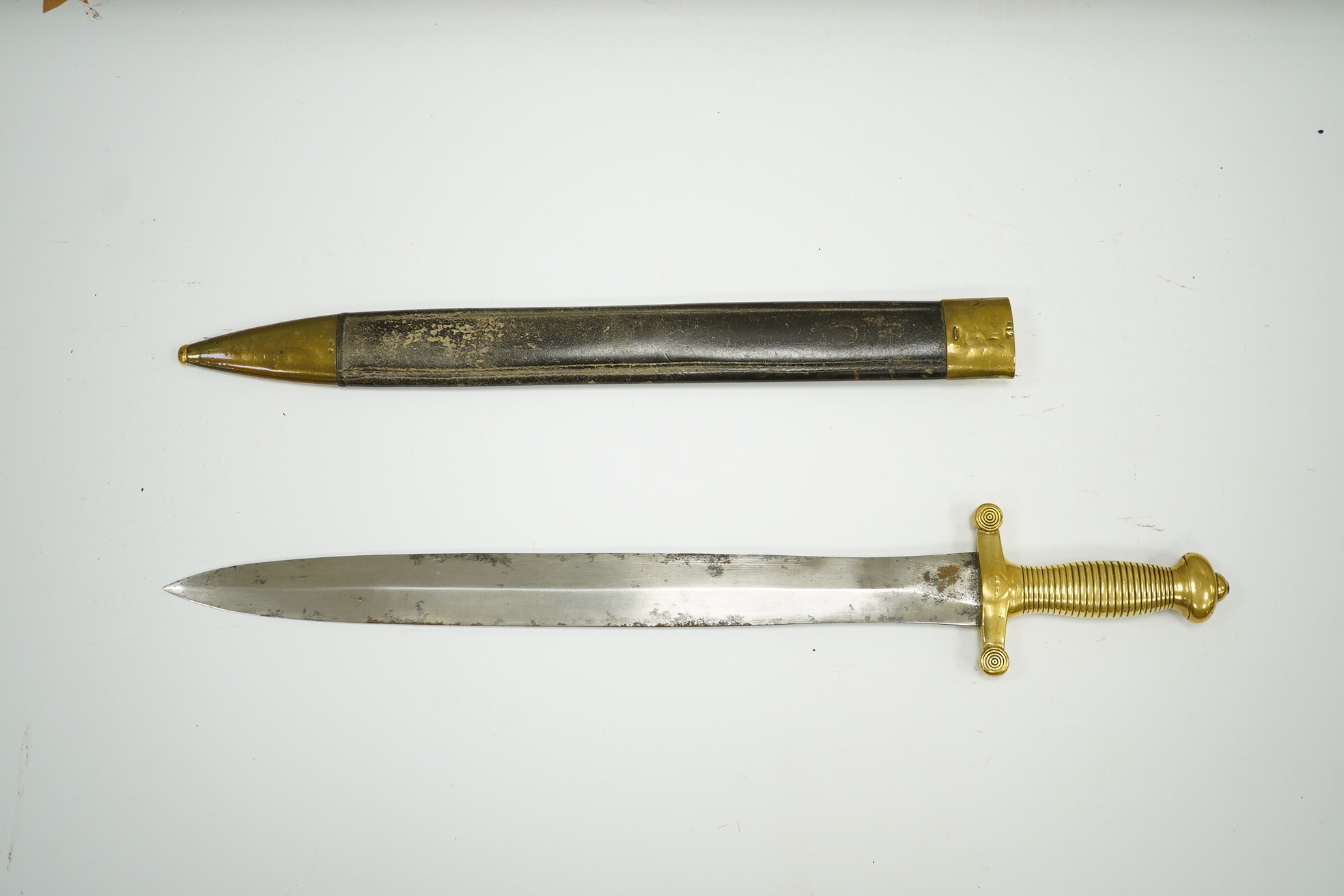 A 19th century French infantryman’s sidearm Gladius with swollen double edged blade, and regulation cast brass cruciform hilt, in its brass mounted leather scabbard, together with a continental bayonet also in scabbard.